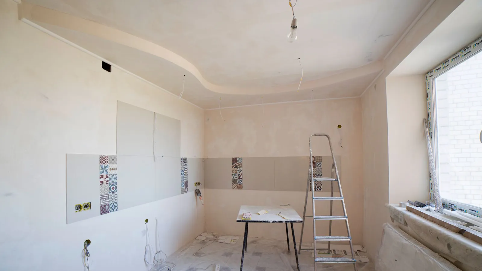 Spacious kitchen under renovation with ladder and tools, showcasing a fresh new design.